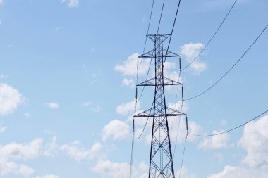 Elektrik kabloları ve mavi gökyüzünün önünde dur işareti olan bir direk..