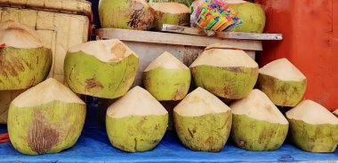 Masada oturan bir grup hindistan cevizinin fotoğrafı, bir masada oturan bir sürü hindistan cevizi var..