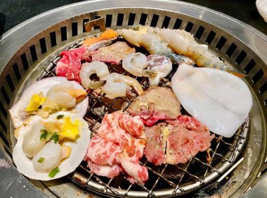 Bir ızgaranın üzerinde çeşitli yemek çeşitleri olan bir fotoğrafı. Üzerinde çeşitli yemek türleri olan bir ızgara var..