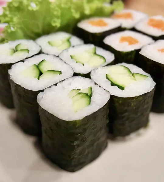 一个用黄瓜和生菜做的寿司盘的照片 在一个用生菜做的盘上有很多寿司卷 — 图库照片
