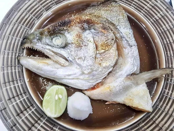 有一张用勺子和里拉的鱼的照片 有一条鱼坐在碗里放些酱汁 — 图库照片