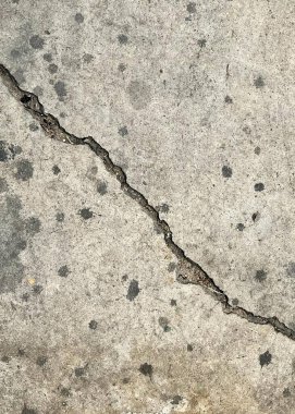 Betondaki bir çatlağın yangın musluğuyla çekilmiş bir fotoğrafı. Yanındaki sarı yangın musluğuyla beton çatlamış..