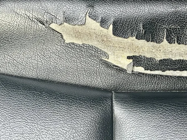 Siyah deri bir kanepenin, üzerinde beyaz ve siyah bir yarasa olan bir fotoğrafı, siyah deri bir kanepenin, beyaz ve siyah bir yarasa tasarımı olan bir yakın çekimi..