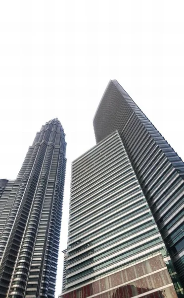 a photography of a couple of tall buildings with a sky background, tall buildings in a city with a clock on the top.