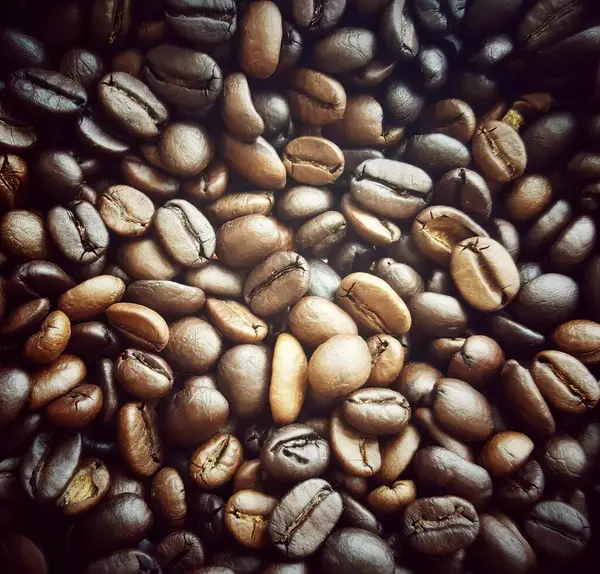 a photography of a pile of coffee beans with a black background, a close up of a pile of coffee beans with a black background.