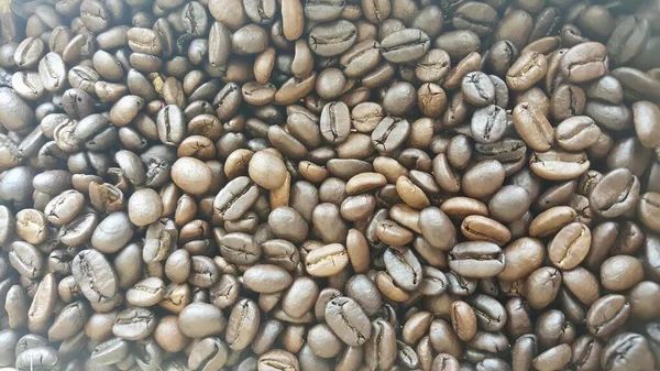 a photography of a pile of coffee beans with a white backgroundof coffee beans are piled together in a pile.
