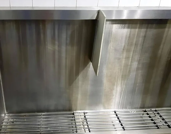 Altında metal ızgara olan paslanmaz çelik bir lavabonun fotoğrafı. Altında metal bir ızgara olan paslanmaz çelik bir lavabo var..