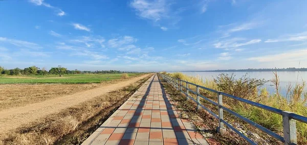 a photography of a walkway leading to a body of water, there is a long walkway that is next to a body of water.