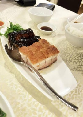 Çatal ve kaşıkla bir tabak yemeğin fotoğrafı. Üstünde et ve pirinç olan bir tabak yemek var..