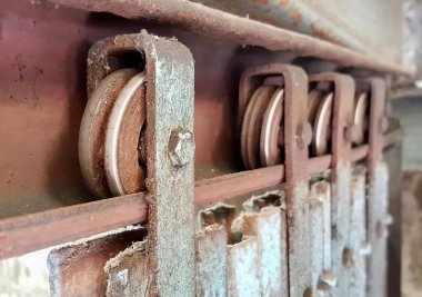 Üzerinde makara olan paslı metal bir kapının fotoğrafı. Paslı metal bir duvarın kenarında iki makara var..