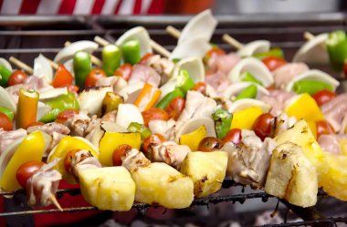 Izgarada et ve sebze şişleri ile çekilmiş bir fotoğraf. Izgarada biber ve soğanlı bir sürü yiyecek var..