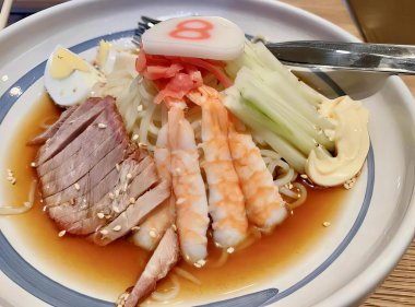 Kaşık ve çatalla bir tabak yemeğin fotoğrafı. İçinde et, sebze ve sos olan bir tabak yemek var..