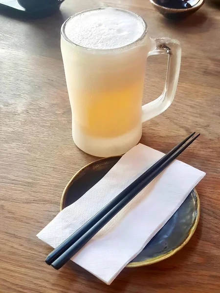 桌上放着一杯啤酒和筷子的照片 盘子里放着一杯啤酒和筷子 — 图库照片