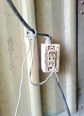 Beyaz bir elektrik prizinin, kabloyla çekilmiş bir fotoğrafı. Üzerinde kablo olan beyaz bir elektrik prizi var..