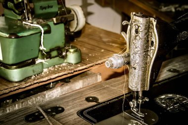 Arka planda yeşil bir makine olan bir dikiş makinesinin fotoğrafçılığı. Masanın üzerinde duran bir dikiş makinesi var..