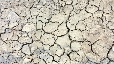 Çatlamış bir yüzeyin, az miktarda kir ve toprak bir yolun çatlak yüzeyine yakın çekim görüntüsü..