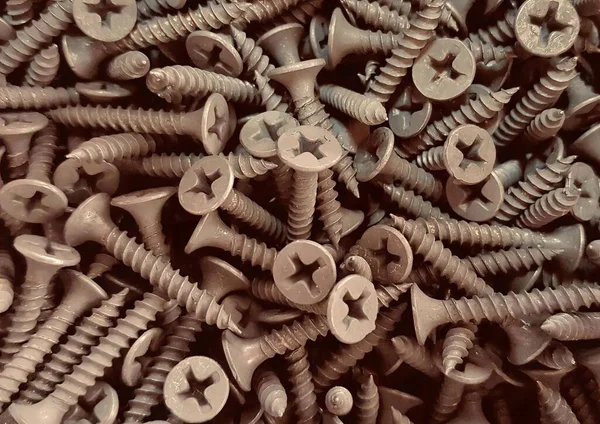 a photography of a pile of screws and nails in a pile, a close up of a pile of screws and nails on a table.