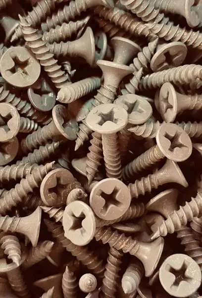 a photography of a pile of screws and nuts on a table, a close up of a pile of screws and nuts on a table.