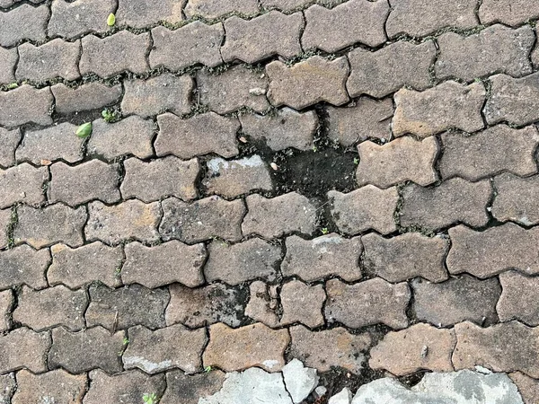 a photography of a brick sidewalk with a hole in the middle,d pavement with cracks and cracks in the middle of it.