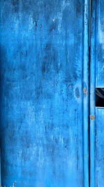 Üzerinde kedi olan mavi bir kapının fotoğrafı. Üzerinde bir kedi olan mavi bir kapı var..