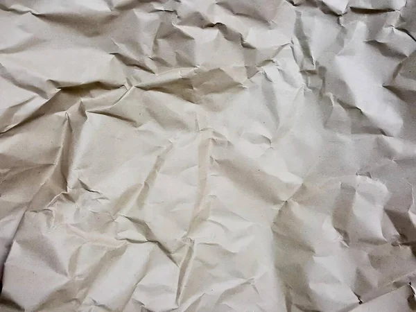a photography of a piece of crumpled paper with a black object in the middle, wrinkled paper with a white background and a black background.
