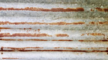 Paslı bir yüzeyin, soluk bir deseni olan, beyaz arkaplanlı metal bir yüzeyde paslanmış bir fotoğrafı..