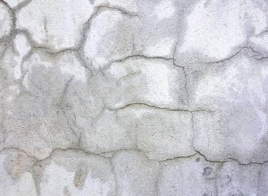 Çimento duvarının tepesinde oturan yangın musluğunun fotografı. İçinde çatlaklar ve çatlaklar olan taş bir duvar..