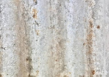 Çimento duvarının tepesinde duran bir yangın musluğunun fotoğrafı paslı ve soyulmuş metal bir yüzey..