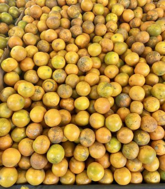 Bir yığın portakalın üst üste konduğu bir fotoğraf, pazarda bir çöp kutusunda portakallar birikir..