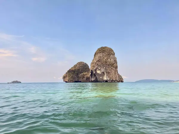 a photography of a rock formation in the middle of the ocean, promontory of a rock formation in the middle of the ocean.