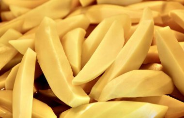 Masadaki dilimlenmiş patates yığınının fotoğrafı, bıçaklı bir tabakta dilimlenmiş patates şişesi..