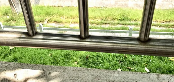 一只猫坐在长椅上凝视着窗外的照片 光秃秃的窗户可以看到一片青草地和一条路 — 图库照片