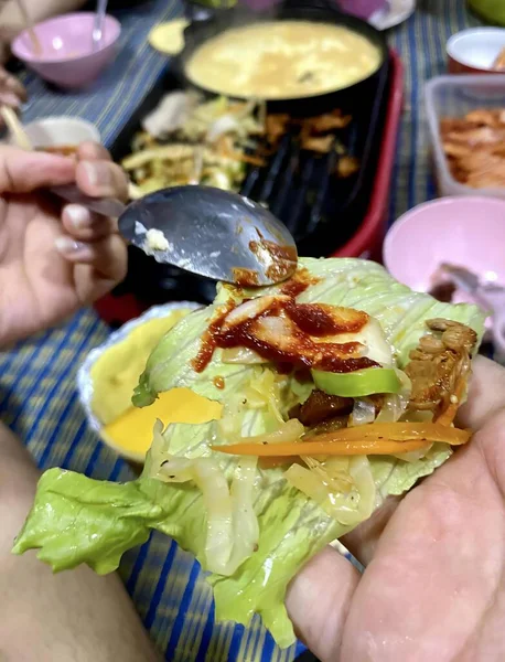 Fotografi Seseorang Memegang Sandwich Dengan Selada Dan Daging Asap Piring — Stok Foto