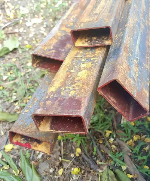 a photography of a pile of rusty pipes sitting on the ground, lumbermill with rust and rusted metal pipes laying on the ground.