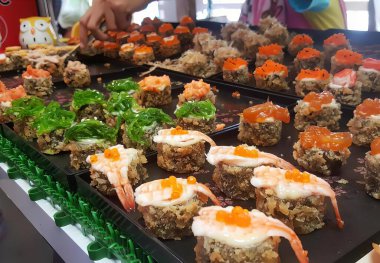 Masada çeşit çeşit suşi, bir tabak karides ve karides soslu suşi..