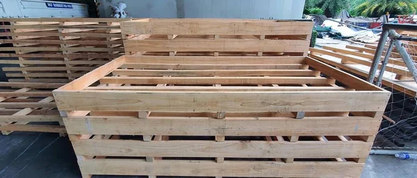 a photography of a pile of wooden pallets sitting on top of a floor, crate pallets stacked on top of each other in a warehouse.
