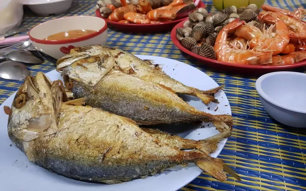 一盘鱼和其他食物放在桌子上的照片 一盘鱼和虾放在有几碗食物的桌子上的照片 — 图库照片