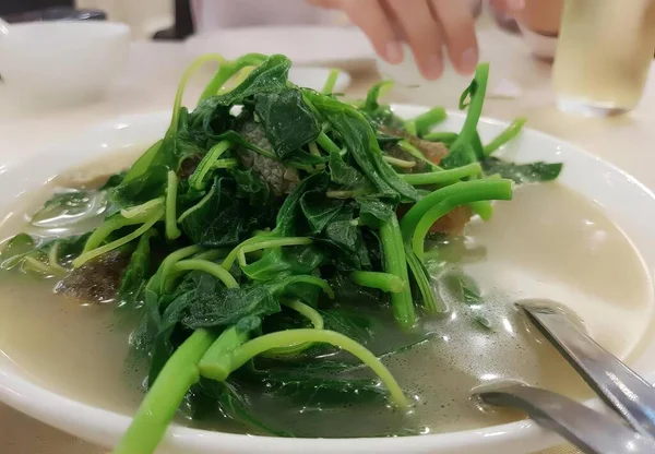 用绿色和勺子做的一碗汤 用绿色和洋葱做的通心粉放在桌上的一碗汤的照片 — 图库照片