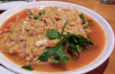 Bir kase çorbanın fotoğrafı, kaşıkla ve çatalla, et ve sebzelerle dolu bir konsommead, masada..