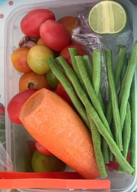 Sebze ve meyve dolu plastik bir kabın fotoğrafı..