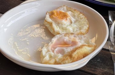 Yumurta ve çatallı bir kase yemeğin, iki yumurtalı bir tabak yemeğin ve masanın çatalının fotoğrafı..