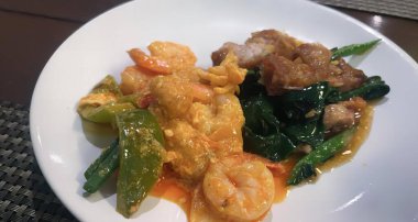 Karides, brokoli ve diğer sebzelerle dolu bir tabak yemeğin fotoğrafı..