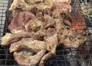 Üzerinde et olan bir ızgaranın ve bir sürü başka etin fotoğrafı. Izgarada bir sürü et var..