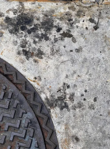 a photography of a manhole with a metal cover and a rusted surface, manhole cover with a hole in the middle of it.