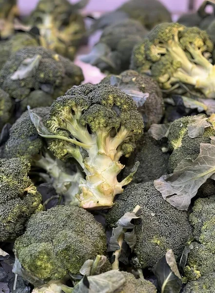 a photography of a pile of broccoli with leaves on it, broccoli is piled on top of each other in a pile.