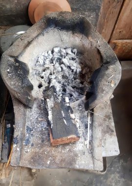 İçinde bir sürü kömür olan büyük bir tencere, içinde büyük miktarda kömür ve ahşap bir blok bulunan bir ocak fotoğrafı..