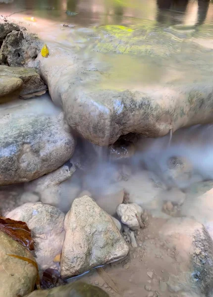 a photography of a stream of water flowing over rocks in a stream, geyser water flowing over rocks in a stream of water.