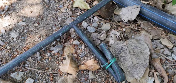 a photography of a broken pipe laying on the ground next to a rock, shovels and a pipe laying on the ground next to a rock.