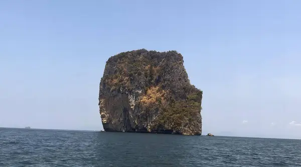 a photography of a rock formation in the middle of the ocean, promontory of a rock formation in the middle of the ocean.