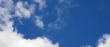 Beyaz bulutlu mavi gökyüzünde uçan bir uçağın fotoğrafı. Arka planda bulutlarla gökyüzünde uçan paraşüt..